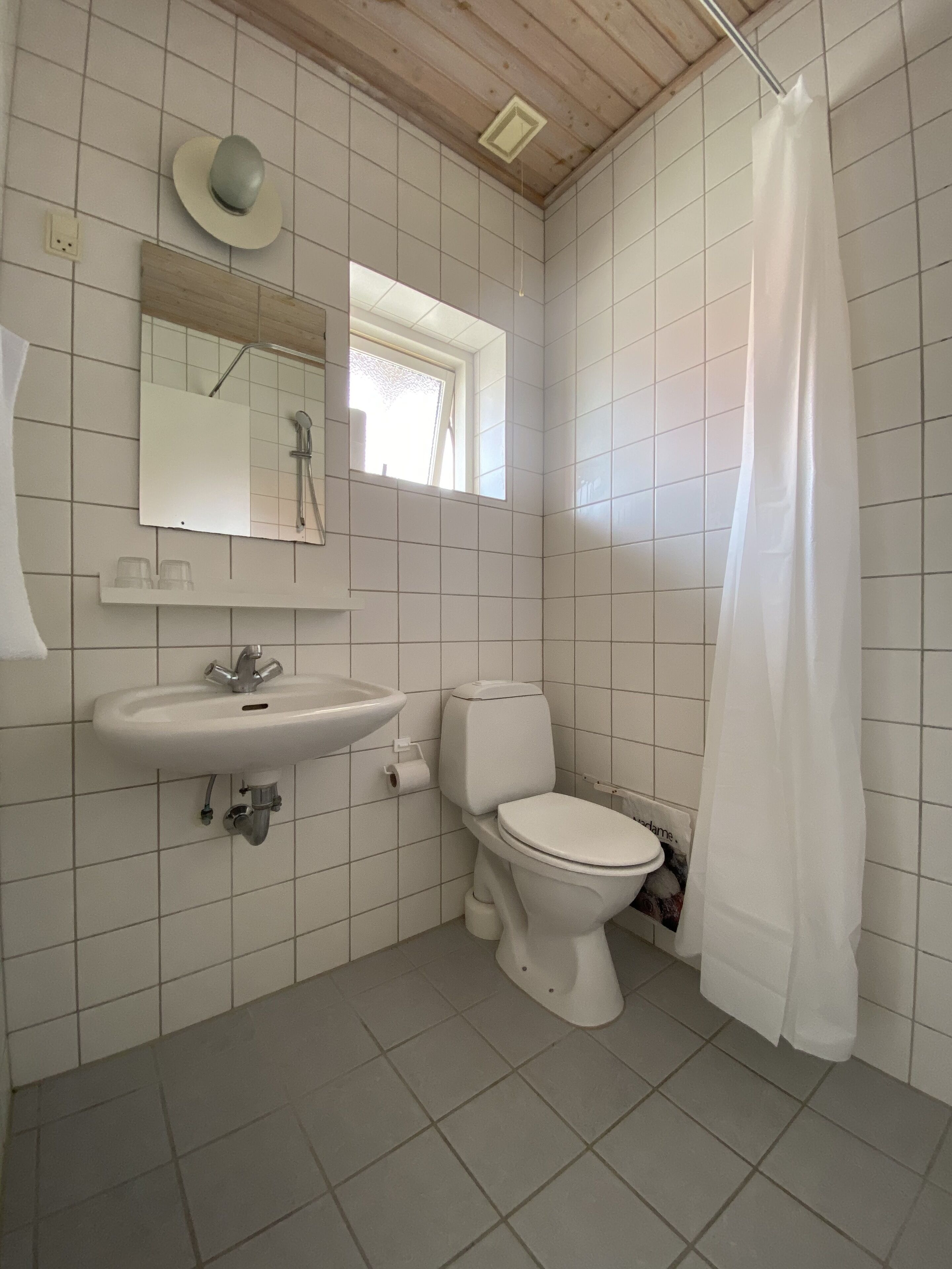 Une salle de bain avec un lavabo blanc, des toilettes et un rideau de douche.