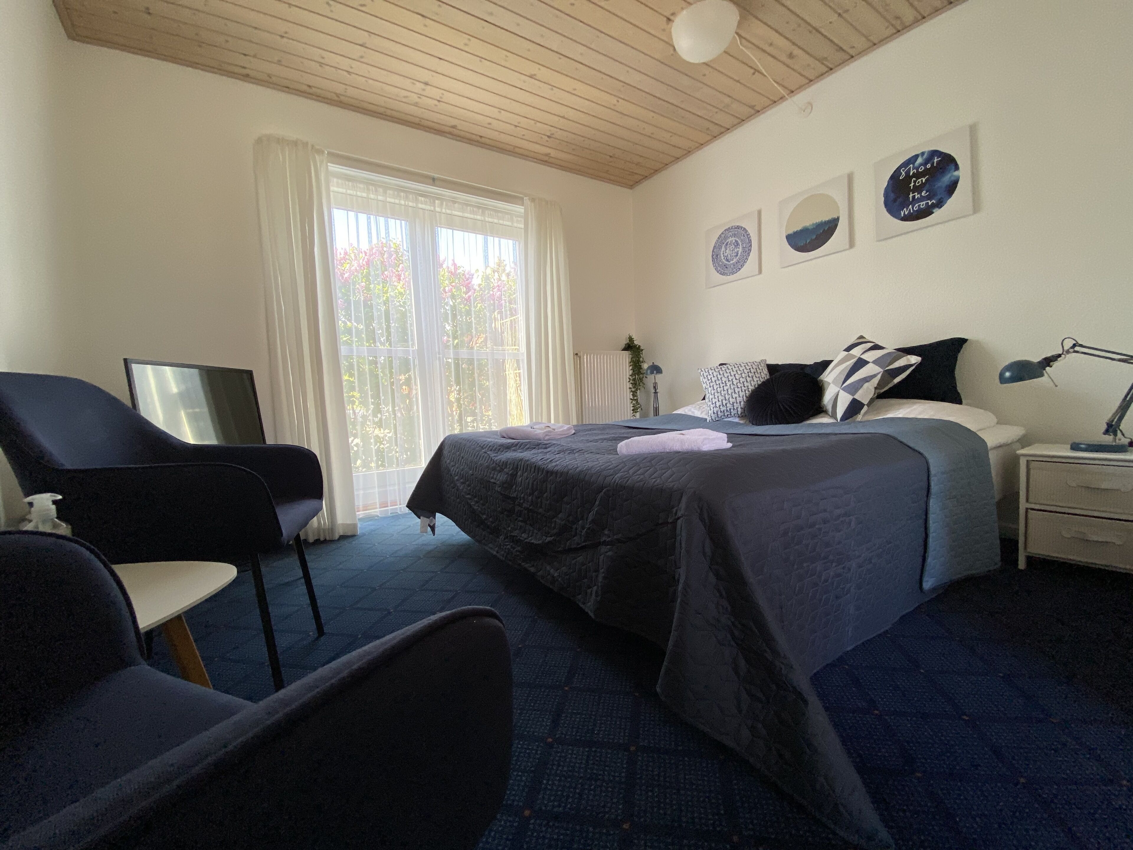 A hotel room with a bed, a chair, a desk, and a window with curtains.