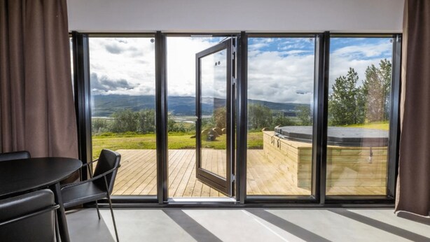 A room with a large sliding glass door leading to an outdoor deck with a view of a mountainous landscape. - Hotel North (Akureyri)
