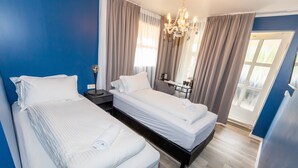 A hotel room with two beds, a desk, and a chandelier. - Hotel North (Akureyri)