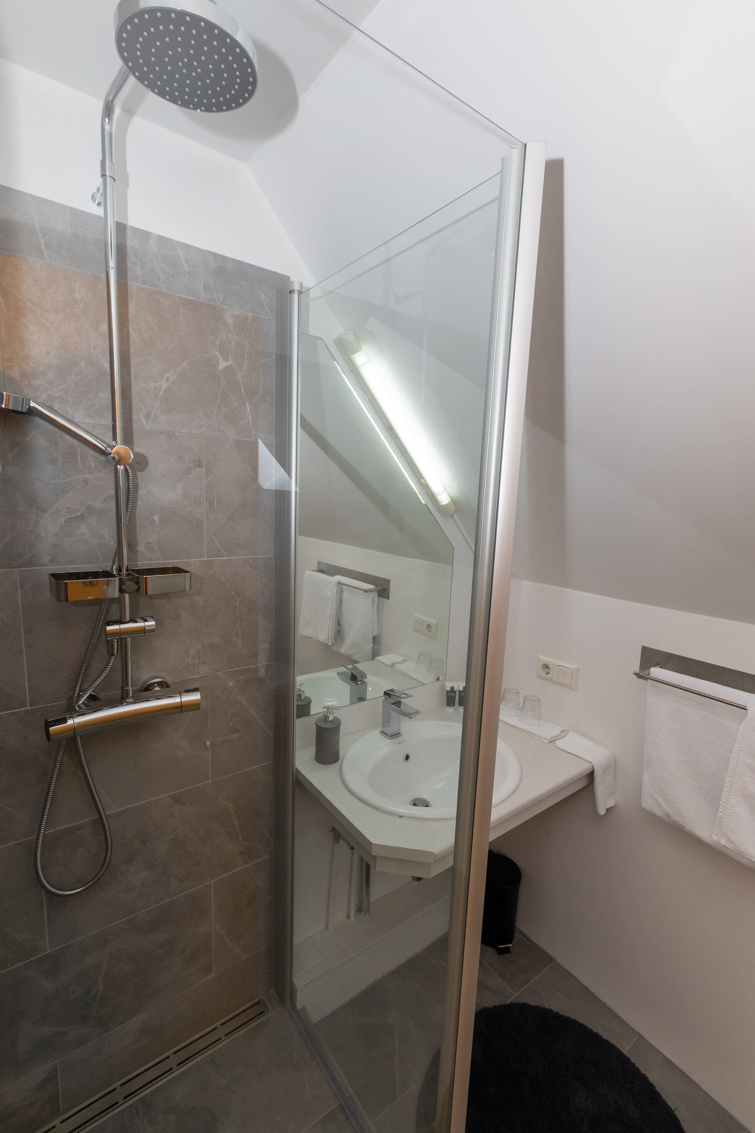 Un bagno moderno con doccia vetrata, lavandino bianco e specchio.