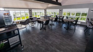 A modern dining area with large windows, dark wood flooring, and contemporary furniture. - Hotel North (Akureyri)