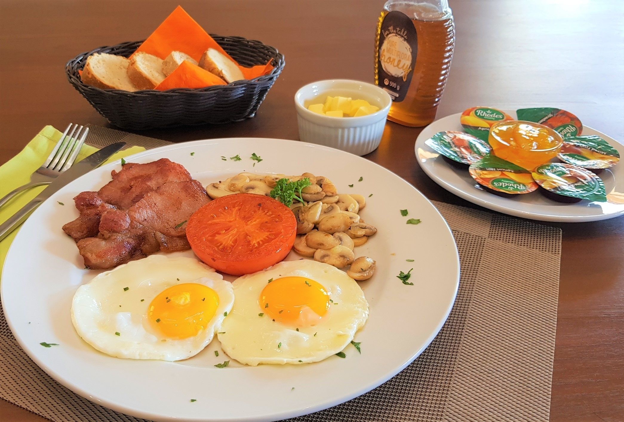 A breakfast plate with eggs, bacon, mushrooms, and a tomato.