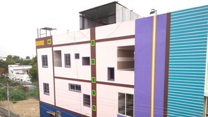A multi-story building with a pink and blue facade, multiple windows, and a visible sign on the lower level. - Sree Guru Sannidhi A Budget Luxury Lodge (Mantralayam)