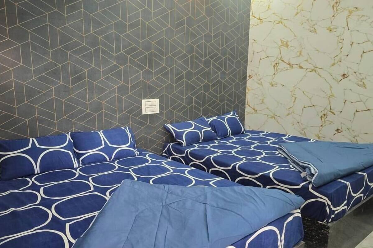 A room with two beds, each with blue bedding and geometric patterns.