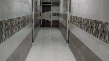 Un pasillo con paredes y piso de baldosas, que conduce a una puerta al final.