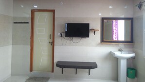 A bathroom with a toilet, sink, mirror, and a flat-screen TV mounted on the wall. - Sree Guru Sannidhi A Budget Luxury Lodge (Mantralayam)