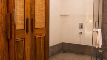 Un baño moderno con ducha de vidrio, puerta de madera con paneles tejidos y un perchero para toallas.