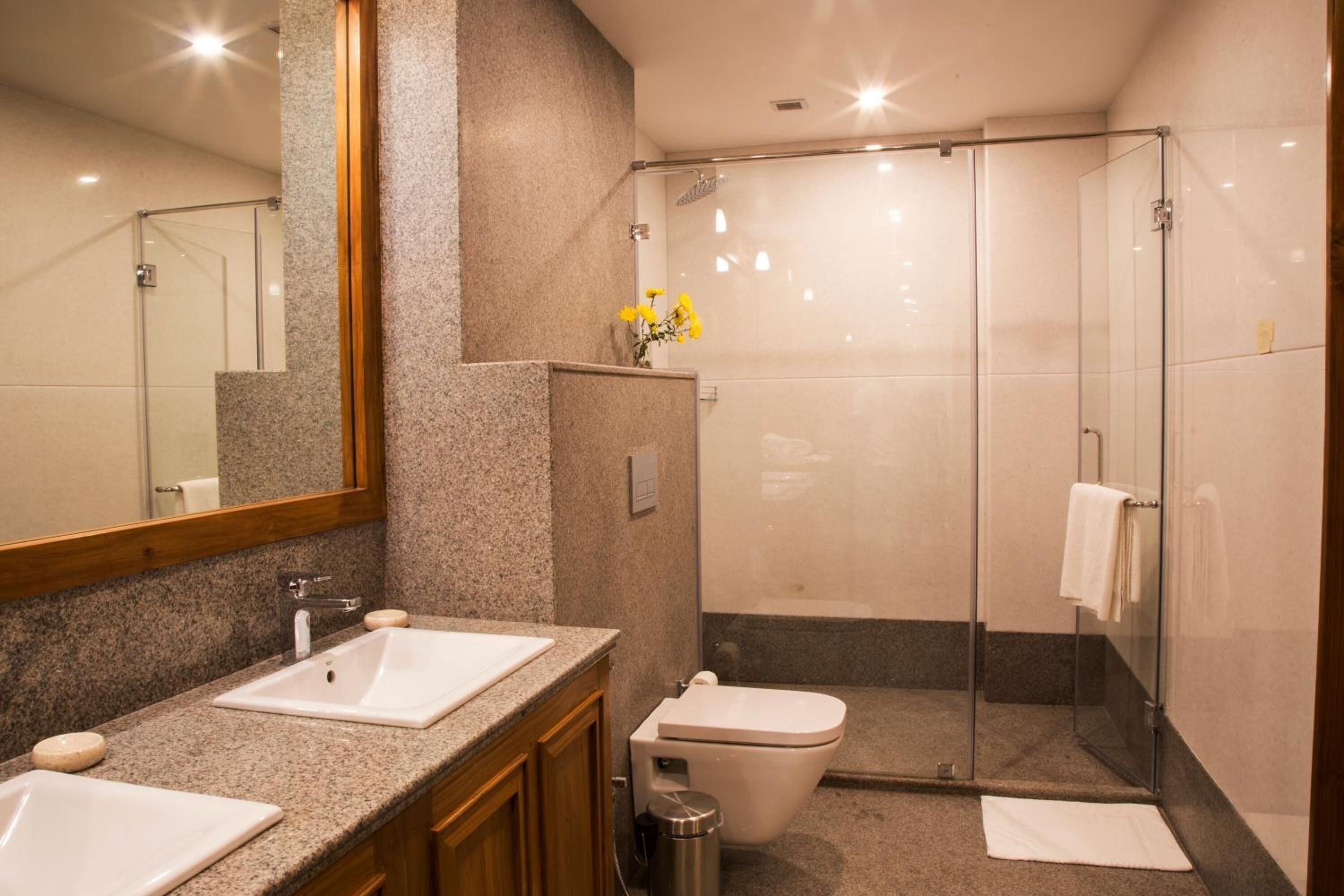 Ein modernes Badezimmer mit zwei Waschbecken, einer Toilette und einer Duschkabine aus Glas.