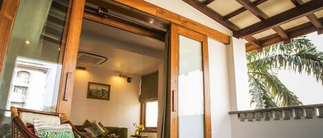A room with a wooden ceiling, a large window, and a view of a palm tree.