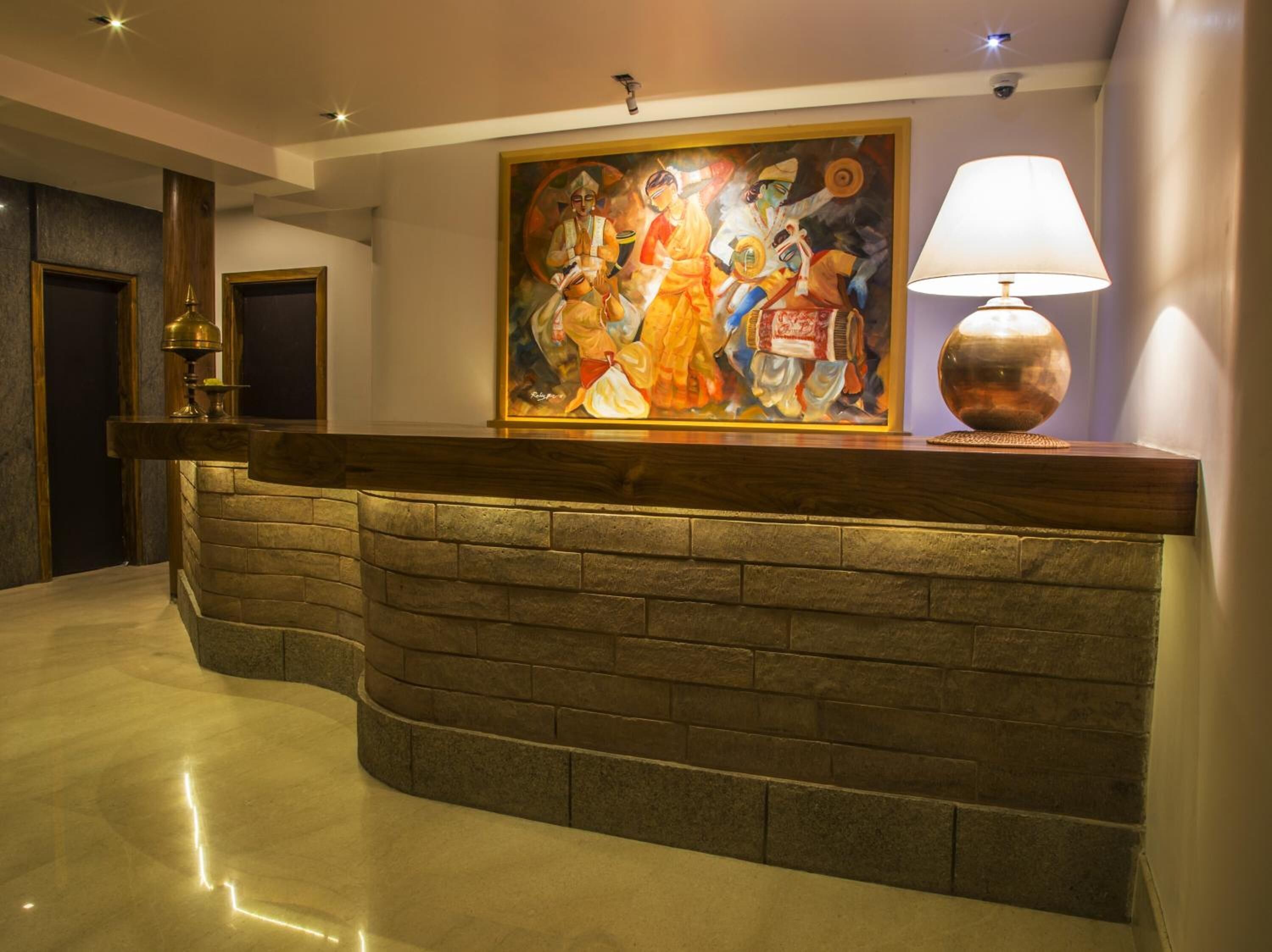 A reception area with a stone counter, a large painting, and a lamp.