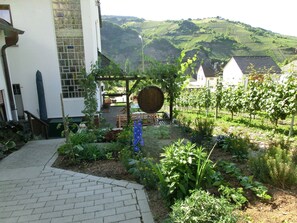 Een tuin met een tegelpad dat leidt naar een wit gebouw met een betegeld raam.