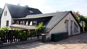 Ein Wohnhaus mit geneigtem Dach, einem Balkon und einem eingezäunten Garten.
