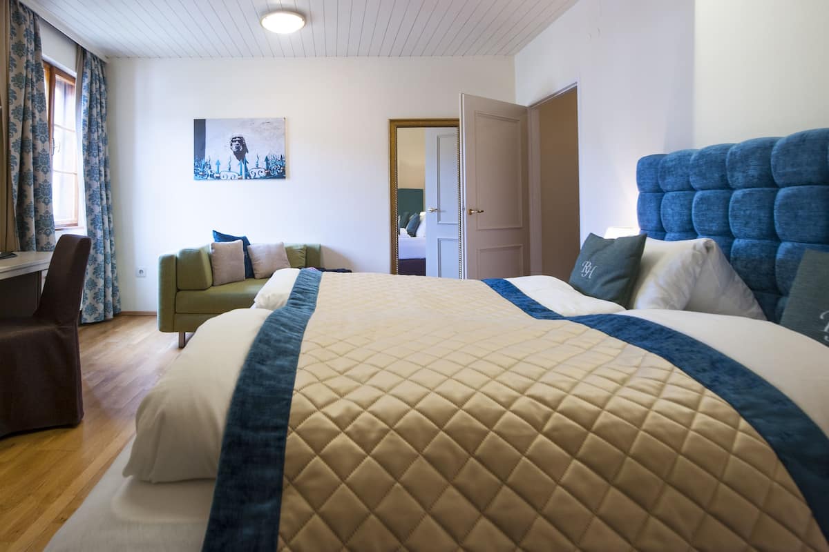 Une chambre avec un grand lit, un bureau, une chaise et un canapé.