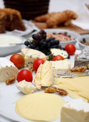 A variety of cheeses, nuts, and fruits on a plate.