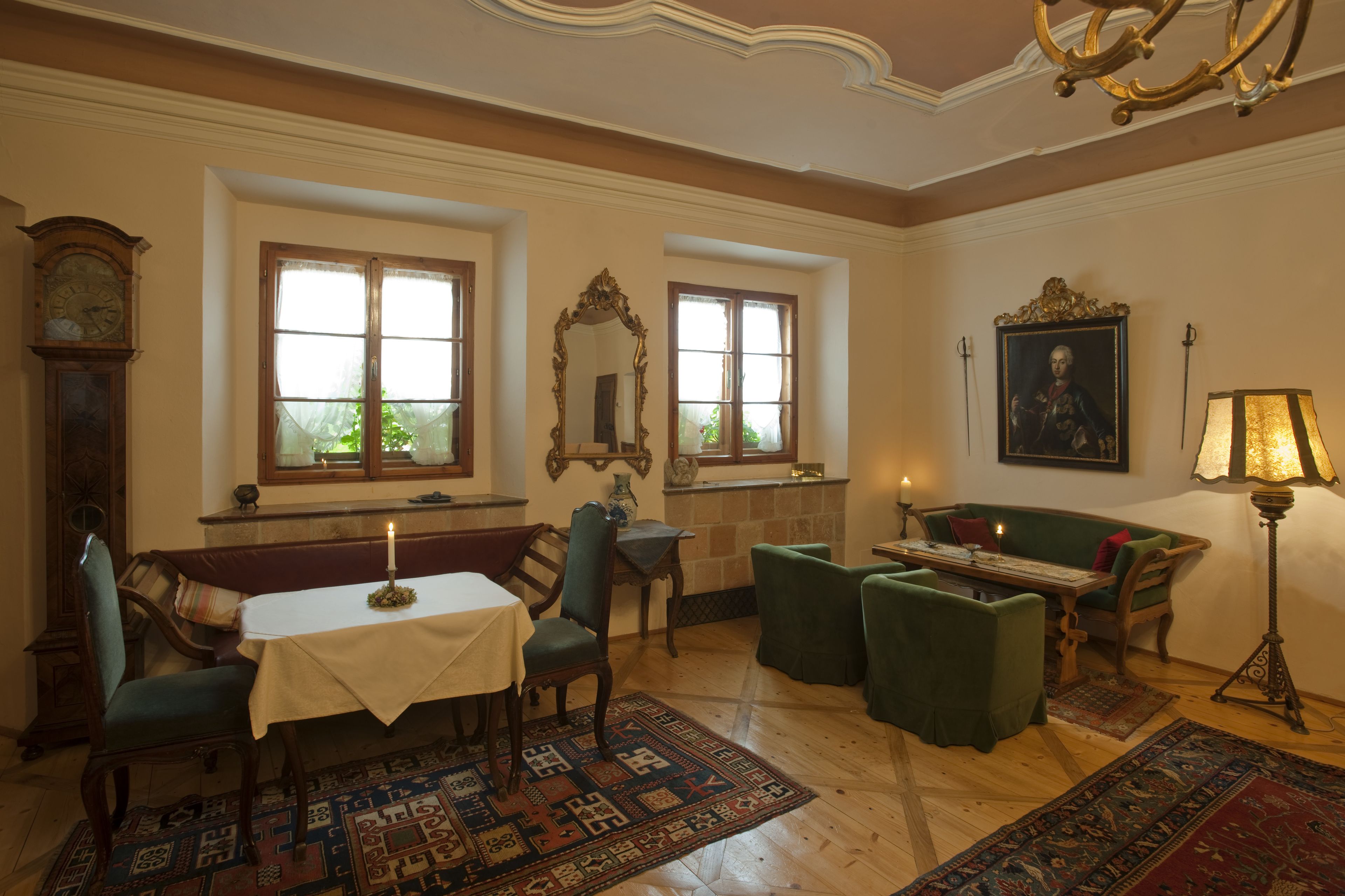 Una habitación con una mesa de madera, sillas, un banco, un espejo, un cuadro y una lámpara.