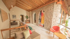 A cozy interior with a stone wall, wooden ceiling, and a seating area with a sofa and chairs. - Mosaic Home - Hostel (Tirana)