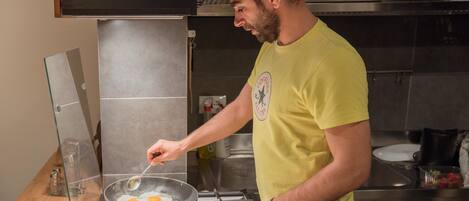 A person cooking eggs in a pan on a stove in a kitchen with a modern design.