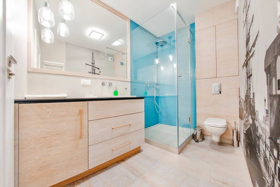 A modern bathroom with a glass shower enclosure, a toilet, and a vanity with drawers.