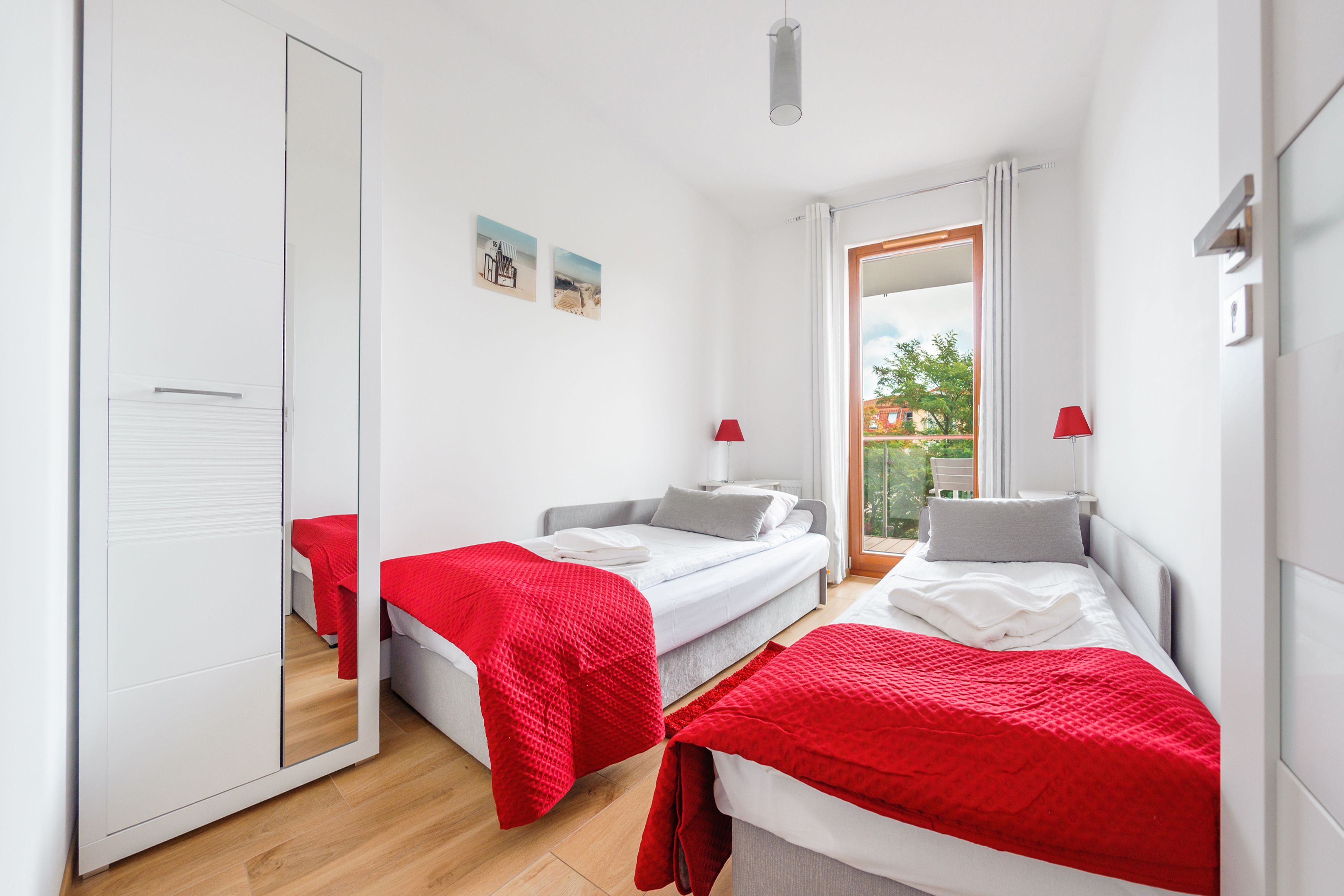 Un dormitorio moderno con dos camas, un espejo grande y vistas al exterior.