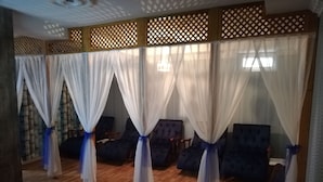 A room with a wooden floor, four dark blue armchairs, and white curtains with blue ties. - Sies Boutique Hotel (Antalya)