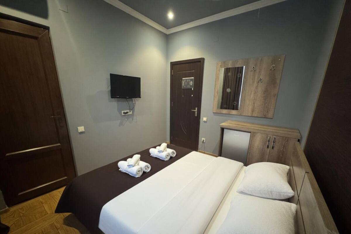 Ein Hotelzimmer mit Bett, Fernseher, Holzschrank und Tür.