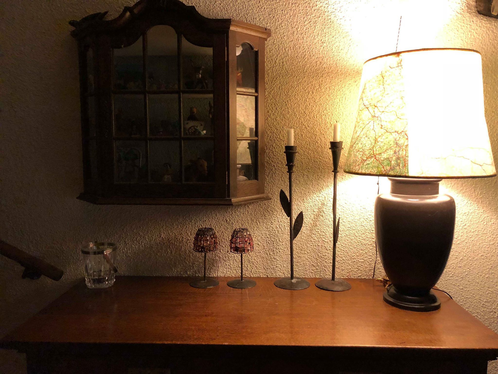 A table with a lamp, candlesticks, and a small glass container.