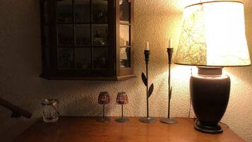 A table with a lamp, candlesticks, and a small glass container.