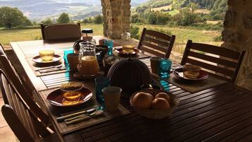 Una mesa de madera lista para el desayuno con una vista panorámica de las montañas.