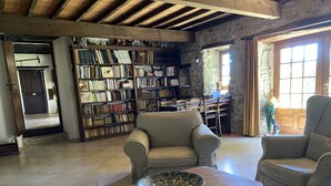 A spacious living room with a large bookshelf, two armchairs, and a wooden coffee table with a decorative bowl. - Week end en Provence - Chambres d'hotes (Comps)