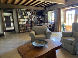 Un salón amplio con una estantería grande, dos sillones y una mesa de centro de madera con un cuenco decorativo.