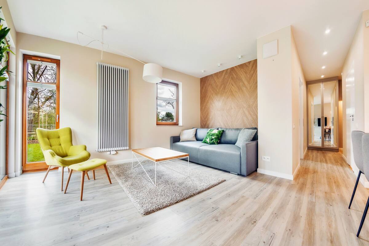 A modern living room with a sofa, a green armchair, a coffee table, and a large window.