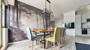 A modern kitchen with white cabinets, a built-in oven, and a large flat-screen TV.