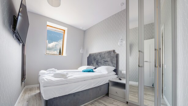 A modern bedroom with a bed, bedside table, and a large mirror.