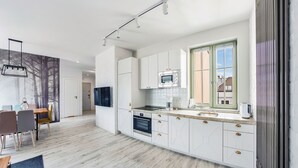 A modern kitchen with white cabinets, a built-in oven, and a large window.