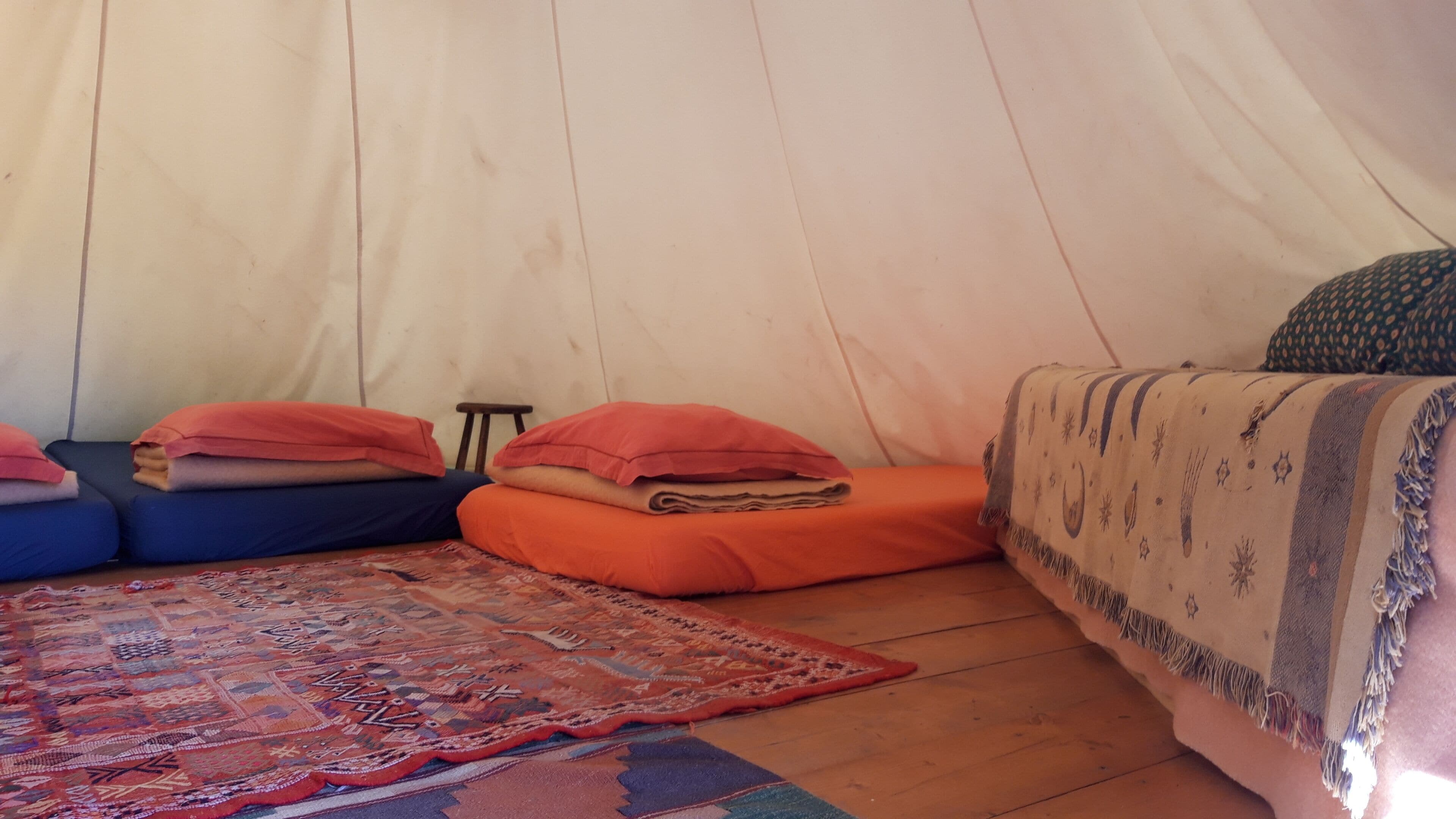 Ein Zelt mit einem gemusterten Teppich, Kissen und einer Decke.