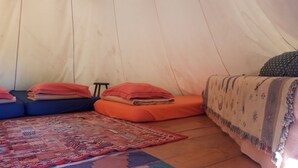 A tent with a patterned rug, pillows, and a blanket. - Weekend en Provence Hébergement Insolite (Comps)