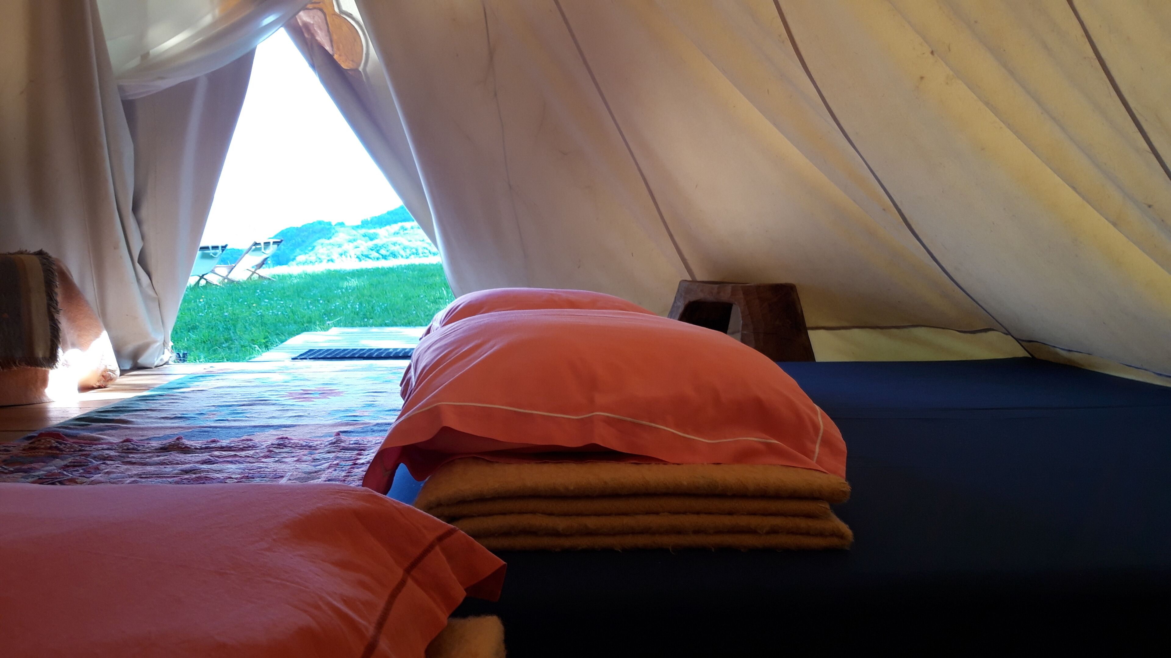 A tent with two beds, one with a blue mattress and the other with a red mattress.
