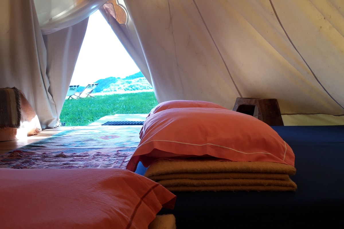Une tente équipée de deux lits, dont l’un a un matelas bleu et l’autre un matelas rouge.
