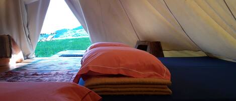 A tent with two beds, one with a blue mattress and the other with a red mattress.