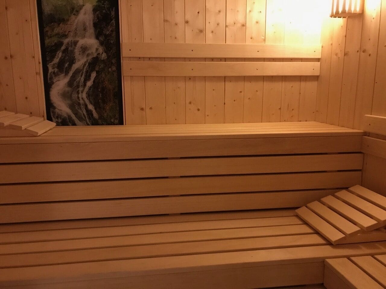 Una sauna de fusta amb bancs i un escalfador fixat a la paret.