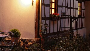 A half-timbered house with visible windows and a light fixture. - Un Soir d'Eté (Ernolsheim-Bruche)
