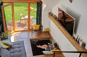 Un interior moderno con un televisor grande, un sofá y una zona de lectura con una hamaca.