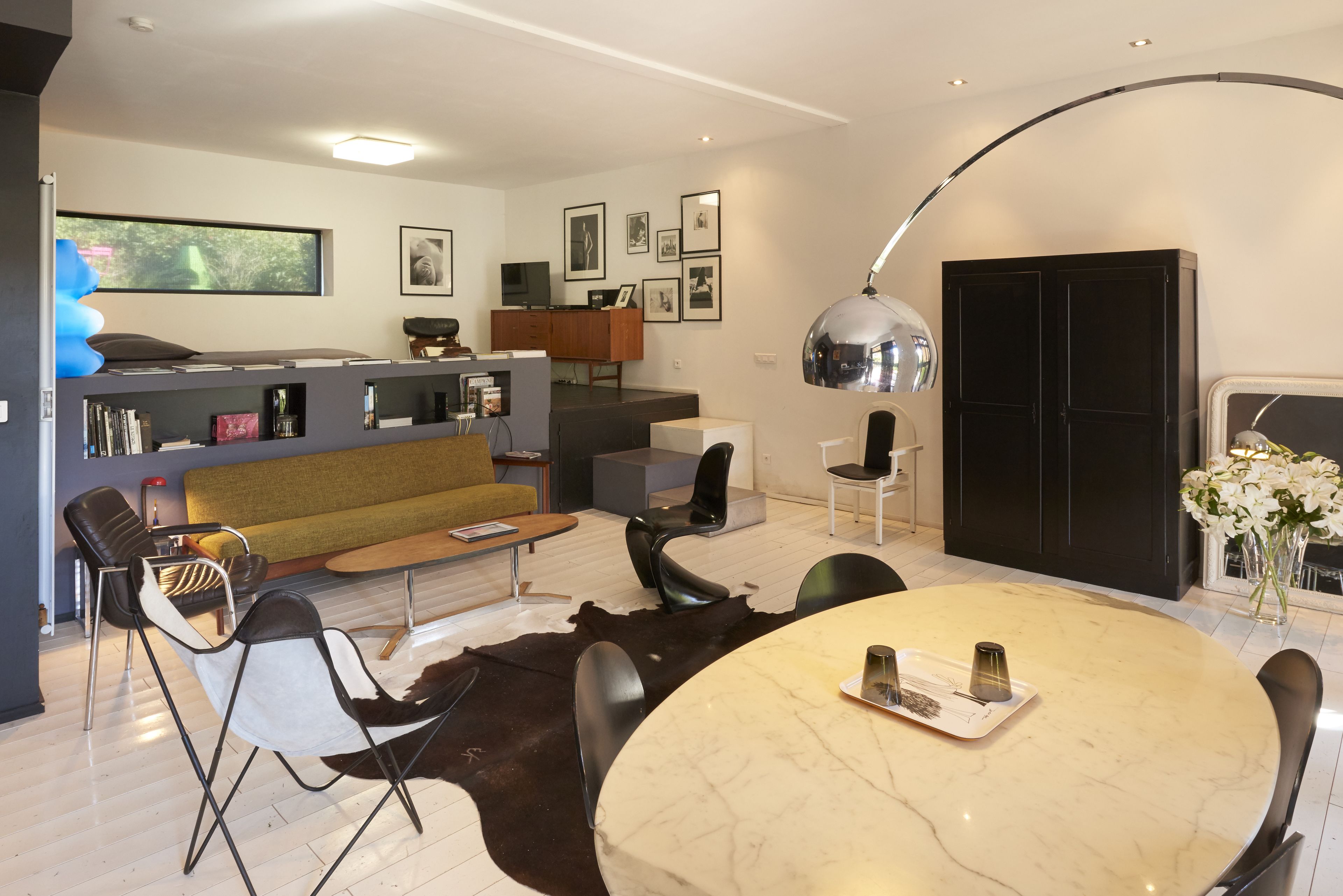 Een moderne woonkamer met een bank, stoelen, een eettafel en een keukenhoek.