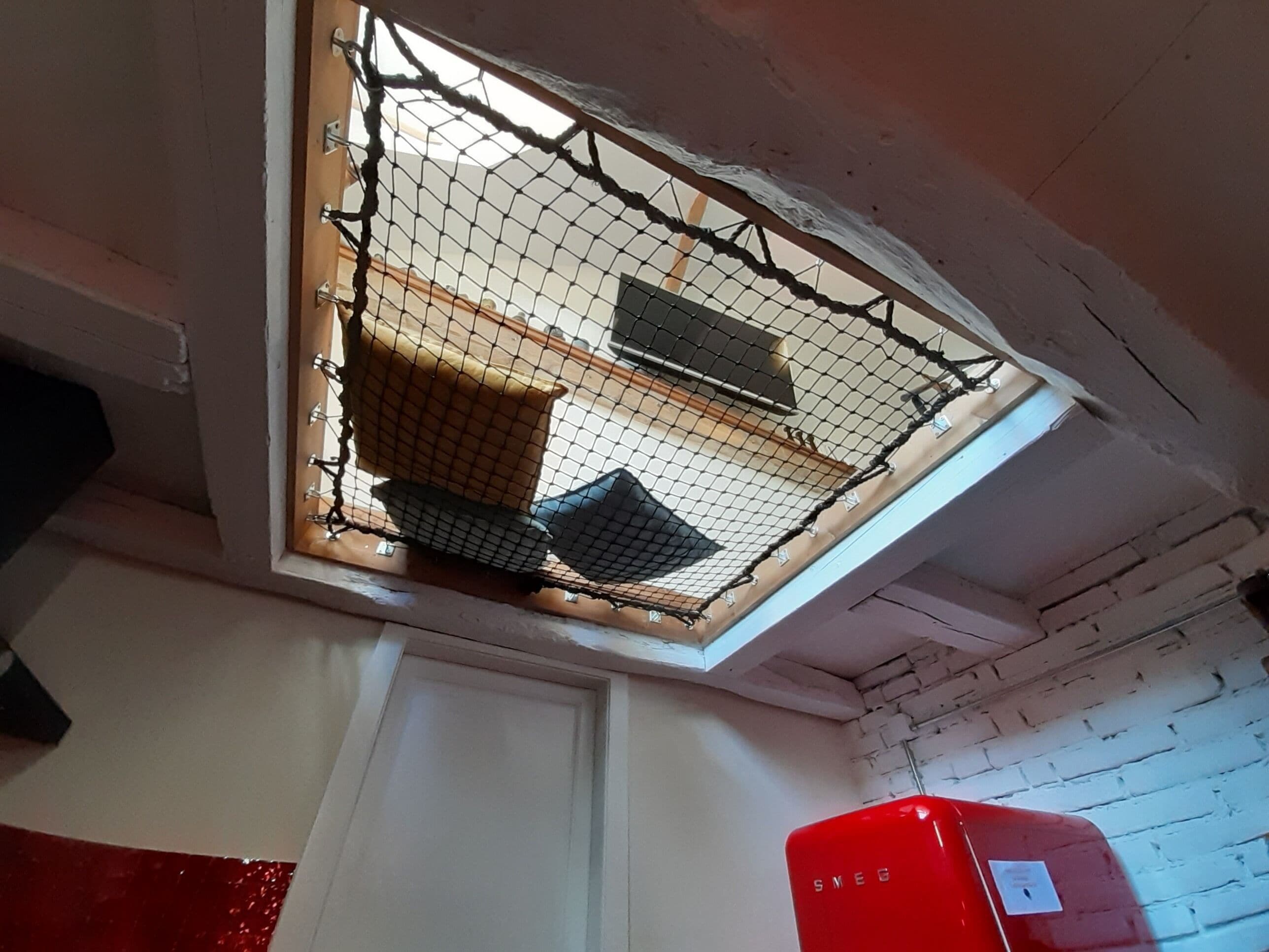 Una habitación con tragaluces, un electrodoméstico rojo y una puerta blanca.