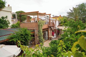 Ein Wohnhaus mit überdachter Terrasse, Ziegelmauern und einem kleinen Garten.