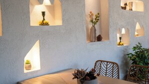 Un comedor con mesa de madera, sillas de mimbre y una planta en maceta.