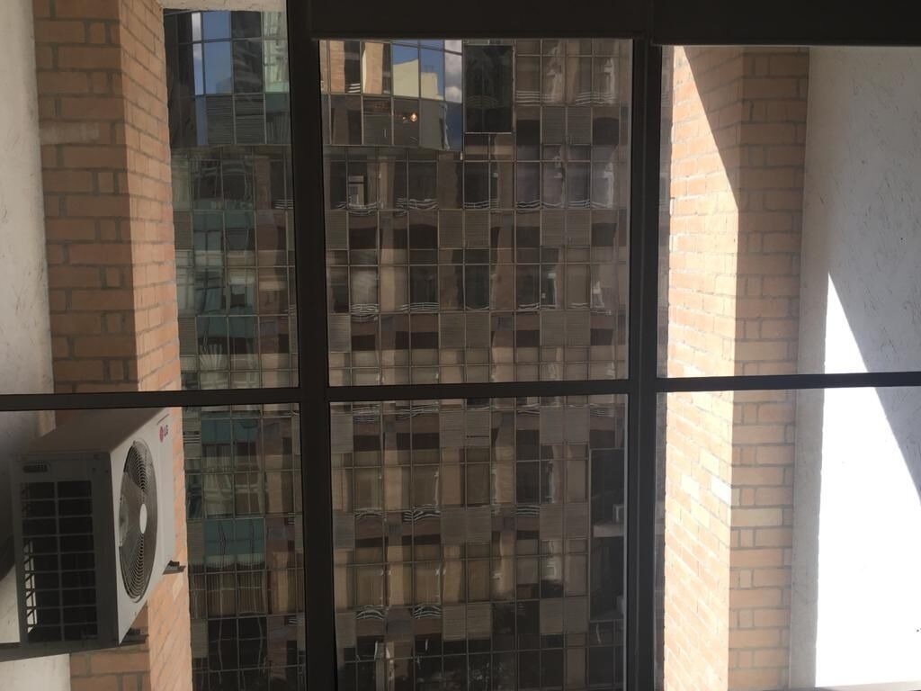 Um edifício com fachada de vidro e unidade de ar condicionado visível.