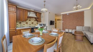 Una cocina moderna con armarios de madera, una mesa de comedor con platos y vasos, y un área de estar con un sofá y una pared decorada con ladrillo.