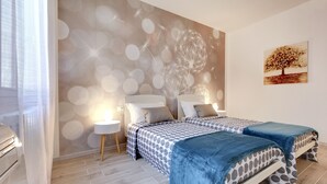 Une chambre avec deux lits, une peinture murale et un tableau.